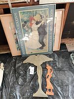 Group shot showing framed Renoir poster, other frames behind, frosted figure and wood carving