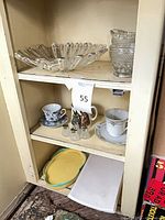 Cabinet shelves showing all items in situ including glass bowl, pressed-glass creamer and sugar, teacups, saucers, shakers, and platters