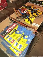 Overall view showing tarp, clamps, booster cables, pry bars, mallet, hammer on tabletop