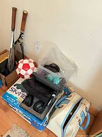 Mixed lot showing tennis rackets, soccer ball, boxed inline skates, boxed Plantronics headphones, bowling ball bag