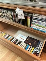 Overall lot showing CDs on shelf, DVD stack, open drawer with cassette tapes
