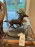 Full view of galloping horse bronze on glass table with glass bowl, stones, candle