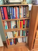 Full view of oak-tone bookcase filled with books