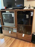 Front view of oak veneer entertainment center showing glass door, wood sliding door, interior shelves, media shelf, two drawers