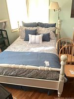 Full view of off-white turned-post bed with mattress, comforter, coverlet and pillows