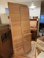 Full view of both hinged louvered wood door panels standing upright