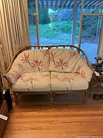 Front view of rattan loveseat with floral cushions