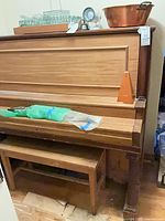 Front view of upright piano with bench underneath and metronome on key cover