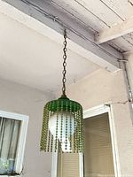 Full view of hanging green beaded pendant light with chain mount