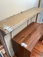 Front view of fireplace surround showing corbels, beadboard panels, chipped paint, and overall structure