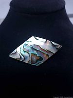 Front of diamond-shaped abalone brooch showing iridescent shell surface