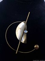 Front view of abstract brass-tone brooch with oval cabochon