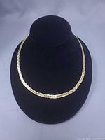 Full view of braided gold-tone serpentine necklace on display bust