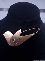 Front view of copper dove brooch on display bust