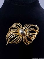 Front view of gold-tone floral brooch on display stand