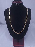 Full view of gold tone curb chain on display bust