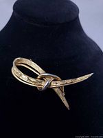 Front view of gold-tone Marboux brooch on display