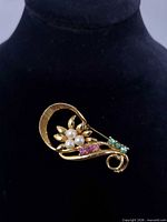 Front view showing gold-tone floral brooch with pearls and rhinestones