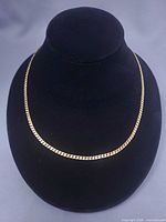 Full view of gold serpentine necklace on display bust