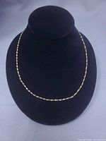 Full view of gold-tone tinsel link necklace on display bust