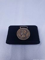 Full view of medal on display pad, showing size and patina