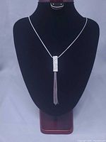 Full view of necklace on display bust showing chain length and pendant with tassel