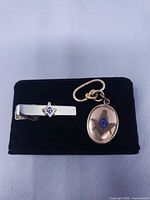 Tie clip and fob displayed on black pad