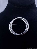 Front view showing overlapping glossy and textured rings with pin