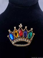 Front view of gold-tone crown brooch with multicoloured rhinestones