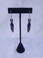 Front view of both cat earrings hanging on stand