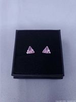 Front view showing both triangular pink stone earrings in box