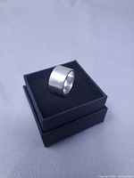 Ring perched on black ring box showing width and plain exterior