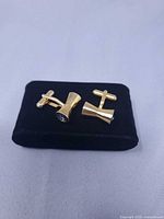Pair of gold-tone cufflinks on black stand