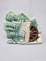 Front view showing raised text, water wheel, fisherman figure