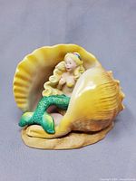 Mermaid seated in conch shell, frontal view