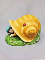 Side view assembled figurine showing snail shell with ladybug and Tom Thumb peeking out