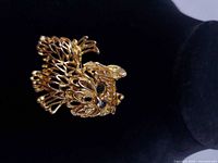 Front view of gold-tone openwork dog brooch showing body details