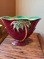 Full view of vase front showing palm tree motif and burgundy glaze