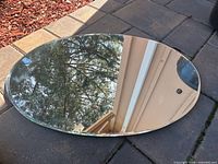 Full view of oval frameless mirror lying flat