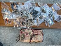 Overview of individually bagged costume jewelry pieces and floral pouch on wooden board