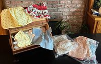 open wooden chest with assorted doll clothes and two bagged assortments