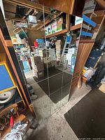 Full view of rectangular mirror with grid pattern leaning against shelving