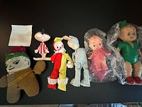 All six dolls lined up on black surface