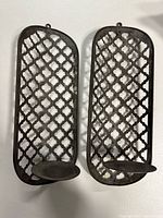 Front view of both metal candle holders showing lattice design and round platforms.