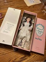 Doll inside open pink box with certificate flap visible