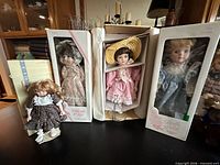 Group view of four porcelain dolls with boxes