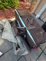 Folded brown portable crib with mesh sides and carrying handles