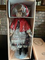 Doll in original box with plastic wrap and stand
