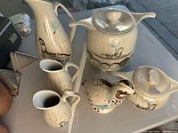 Group shot of three pitchers, two covered casseroles, quail holder