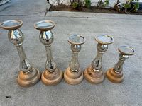 All five candle holders front view showing graduated heights and materials
